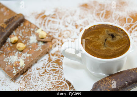 Tasse de café avec une mousse en forme de coeur subtilement décorées de fleurs et de chocolat en forme de banane Banque D'Images