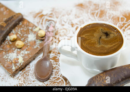 Tasse de café avec une mousse en forme de coeur subtilement décorées de fleurs et de chocolat en forme de banane Banque D'Images