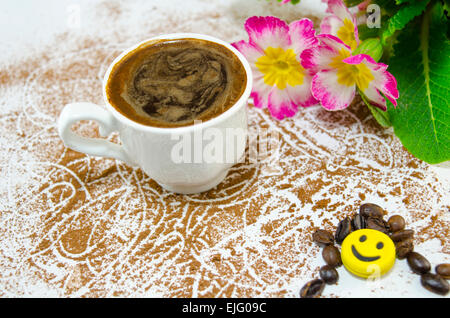 Tasse de café avec une mousse en forme de coeur subtilement décorées de fleurs et de chocolat en forme de banane Banque D'Images