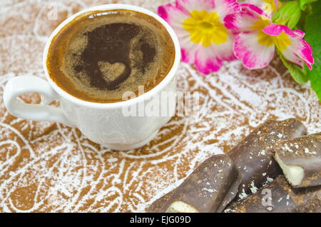 Tasse de café avec une mousse en forme de coeur subtilement décorées de fleurs et de chocolat en forme de banane Banque D'Images