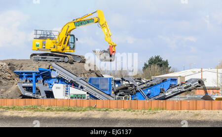 Mechanical digger sur un monticule de terre avec de la terre de la bande de transport. Banque D'Images