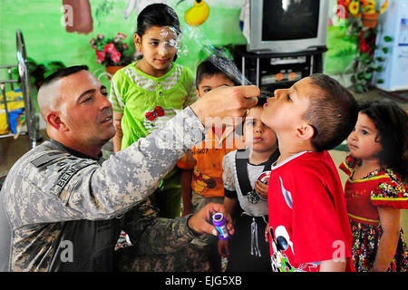 Maître de l'armée américaine le Sgt. Mike Bennett aide un garçon irakien Blow bulles à Al UNE Alahbab Jaeffer dans l'école, de l'Iraq, le 21 avril 2009. Bennett est affecté à la 8e Brigade de police militaire. Airman Senior Daniel Owen Banque D'Images