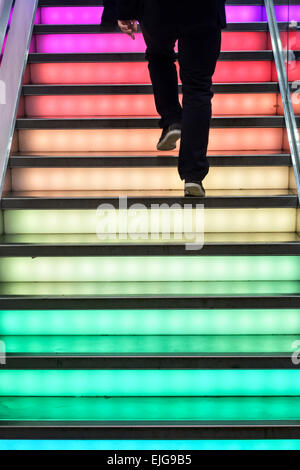 Un homme à monter un escalier lumineux colorés au fashion store Uniqlo, Regent Street dans le West End de Londres Banque D'Images