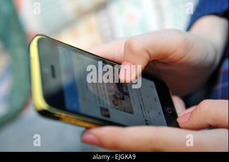 Adolescente surfe sur le web sur son mobile iphone UK Banque D'Images