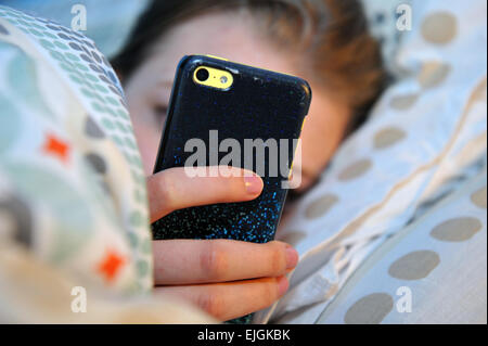 Teenage girl utilise son téléphone portable la nuit au lit. Banque D'Images