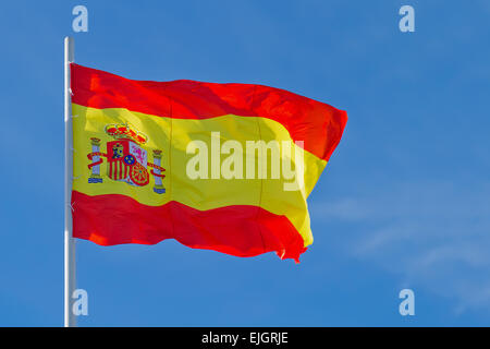 Brandissant le drapeau de l'Espagne est en face de ciel bleu Banque D'Images