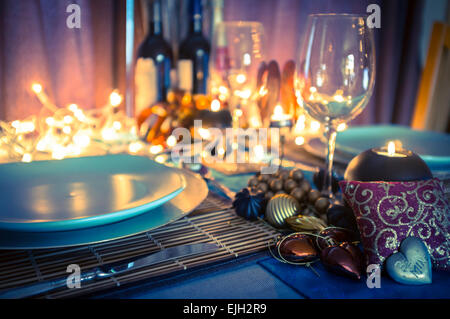 Réglage de la table et décoration pour dîner romantique avec des bougies, des bouteilles de vin, de verres à vin et des feux chauds Banque D'Images