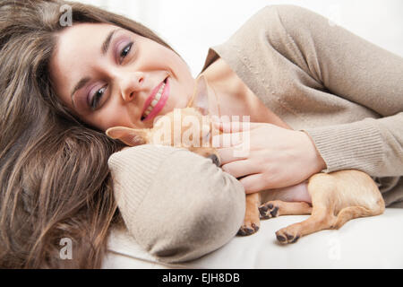 Belle jeune femme aimant son chiot dans sa salle de séjour Banque D'Images