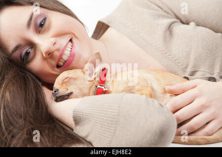 Belle jeune femme aimant son chiot dans sa salle de séjour Banque D'Images