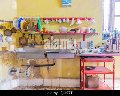 Une vue de l'évier et tasses et plats stockés au-dessus de lui dans une cuisine d'une maison cubaine. Banque D'Images