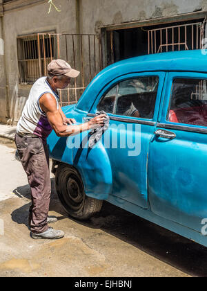 Un homme afro-cubaine et nettoie le turquoise 1950 Chevrolet 4 portes à l'extérieur de l'automobile dans la Habana Vieja. Banque D'Images