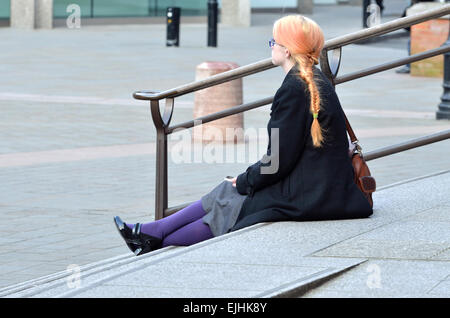 Londres, Angleterre, Royaume-Uni. Jeune femme avec des cheveux orange et violet-assis sur les marches de la cathédrale de Wesminster Banque D'Images