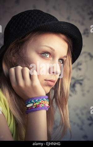 Portrait de belle blonde woman in black hat et à tisser en caoutchouc bracelets, tons vintage photo, effet de style instagram Banque D'Images