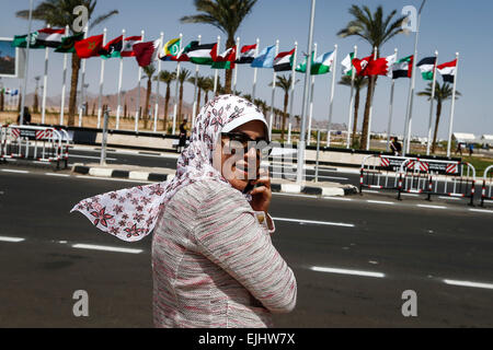 Charm el-Cheikh, en Egypte. Mar 27, 2015. Un Egyptien femme parle au téléphone en face de drapeaux des pays membres de la Ligue arabe à l'extérieur du centre de conférence à Charm el-Cheikh, Egypte, le 27 mars 2015. Le sommet de la Ligue Arabe se tiendra à Charm el-Cheikh du 28 mars au 29. Credit : Cui Xinyu/Xinhua/Alamy Live News Banque D'Images