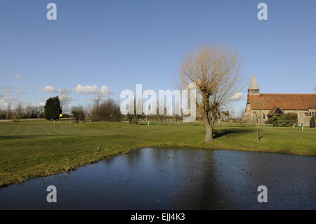 Vue sur l'étang sur le 1er trou au livre vert et une petite église Burnham-on-Crouch Angleterre Essex Golf Club Banque D'Images