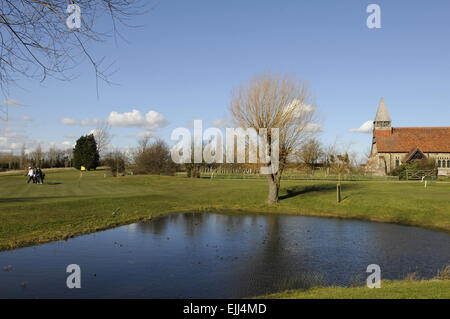 Vue sur l'étang sur le 1er trou au livre vert et une petite église Burnham-on-Crouch Angleterre Essex Golf Club Banque D'Images