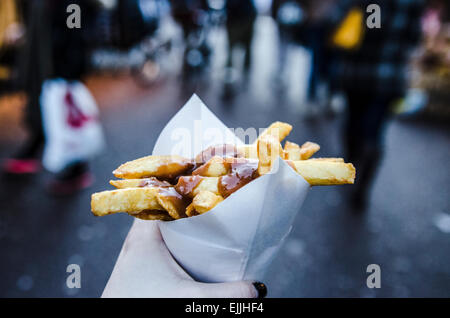 Main tenant un cornet de frites en sauce satay à Amsterdam aux Pays-Bas. Banque D'Images