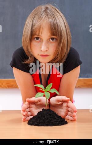 Fille de l'école élémentaire grave la protection de plus en plus de plantes rares de tas de saleté Banque D'Images