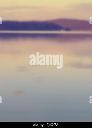 Arrière-plan flou d'un lac calme avec la forêt et les collines dans l'arrière-plan lointain. Conçu pour fonctionner avec affichage de texte Banque D'Images