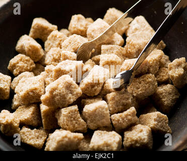 Cubes de sucre de canne dans le bol sur la table en bois. Banque D'Images