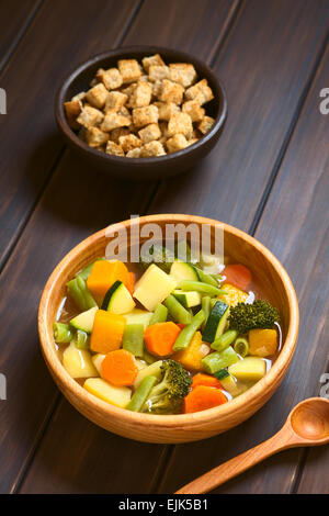 Bol en bois de soupe de légumes faite de courgette, haricot vert, carotte, brocoli, pomme de terre et la citrouille avec un petit bol de croûtons Banque D'Images