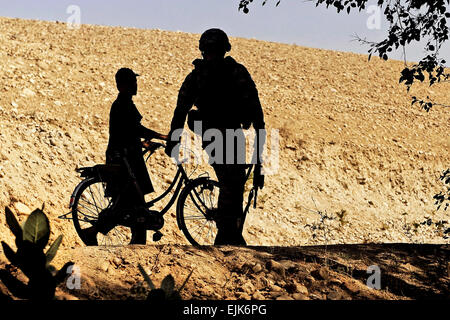 Le sergent de l'armée américaine. 12818 Sterling, chef d'équipe rattaché à l'Équipe de reconstruction provinciale de Laghman promenades et parle avec un garçon afghan dans Alisheng district, province de Laghman, 12 septembre. L'EPR, en partenariat avec les forces de sécurité et de l'équipe assistant la Police nationale afghane, patrouillée par un village pour parler à la population locale et d'enseigner les procédures appropriées de la PNA au cours de patrouilles. Banque D'Images