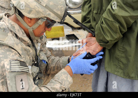 Le sergent de l'armée américaine. Marvin Mendia empreintes digitales d'un détenu dans Gavband village dans la province de Helmand en Afghanistan, le 27 février 2010. Des policiers afghans et des soldats américains mènent des opérations conjointes de sécurité le long de la route 601 pour appuyer l'opération 601 Cougar. Mendia est affecté au 4e Bataillon, 23e Régiment d'infanterie. Le s.. Christine Jones Banque D'Images