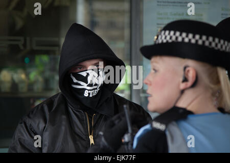 Le démonstrateur masqué au rassemblement néo-nazi du Front national et à la démonstration de la fierté blanche de Piccadilly Manchester affronte une policewoman. Des arrestations ont eu lieu jusqu'à l'extrême-droite du groupe "White Pride", qui s'est réuni à Manchester pour organiser une manifestation. Près de 50 membres du groupe agitent des drapeaux et défilent à travers les jardins de Piccadilly. Les militants anti-fascistes ont organisé une contre-manifestation avec la police séparant les deux camps. La police du Grand Manchester a déclaré que deux arrestations avaient été effectuées, l'une pour violation de la paix. La seconde a également été tenue sur une infraction d'ordre public. Banque D'Images