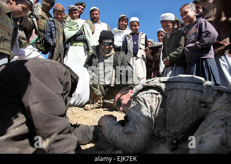 Un soldat de l'armée américaine prend une pause à bras de fer un Afghan lors d'une patrouille pour vérifier sur les conditions dans le village de Yawez dans la province de Wardak, Afghanistan, le 17 février 2010. Les gens du village prendre un défi amical. Les soldats sont affectés à la 405e Bataillon des affaires civiles. Le Sgt. Gilchrest Russell Banque D'Images