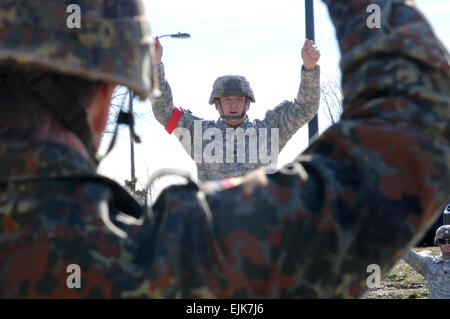 Une Division Aéroportée allemande Paratrooper suit le long de premier plan comme premier Sgt. David Dean, une batterie, 2e Bataillon, 321e Régiment d'artillerie de l'air, 4e Brigade Combat Team, 82e Division aéroportée, effectue le saut de la formation avant d'une opération aéroportée de nuit, le 13 janvier, 2014. Les parachutistes allemands ont été présentés avec des ailes aéroportées américaines à la suite de l'opération. Les parachutistes allemands s'est rendu à Fort Bragg, Caroline du Nord, afin de mieux comprendre le type de formation la 82e mène dans l'espoir d'envoyer plus de soldats allemands pour former avec leurs homologues américains dans le futur Banque D'Images
