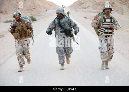 Un soldat de l'Armée américaine affecté à la Compagnie Charlie, 703e Bataillon de soutien de la Brigade, 4e Brigade d'aider et de conseiller, 3e Division d'infanterie, promenades avec des soldats iraquiens au cours d'une route mars dans le cadre d'un exercice d'entraînement à Al Asad Air Base, l'Iraq, le 4 mai 2011. La formation a été donnée aux Irakiens dans le cadre de l'opération nouvelle aube. La FPC. Brian Chaney, de l'armée américaine. Publié Banque D'Images