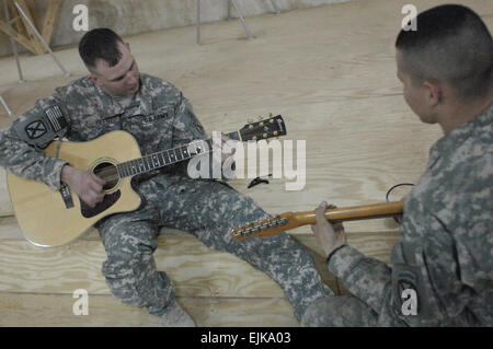 Ccp de l'armée américaine. Eric Pettit, et Charles Jones, affectés au Siège, Peloton Bravo Batterie, 5e Bataillon, 25e Régiment d'artillerie, 4e Brigade, 10e division de montagne, jouer de la guitare ensemble au poste de sécurité commune, Babel Karadah, Bagdad, Irak, le 18 mars 2008. Le s.. Jason T. Bailey Banque D'Images