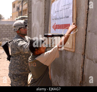 Le s.. Robert Groves, un Boulder City, Nevada, les autochtones, les ongles un signe en place comme un garçon irakien lui permet de le tenir. Le signe indique les visiteurs à l'ouverture récente du Centre des opérations civiles et militaires sur la sécurité commune de Sadr City Station dans le nord-est de Bagdad, le 27 avril. Groves est un sergent de la prévôté dans la 3 Brigade Combat Team, 4e Division d'infanterie, Division multinationale - Bagdad. ID : 86155 Date : avril 27th, 2008 Location : Bagdad, IQ Photographe : Sgt. Zachary Portefeuille MottView Banque D'Images