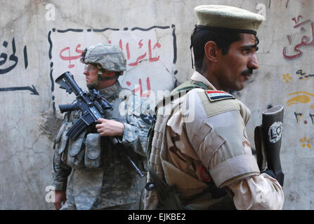 Un soldat de l'armée irakienne avec le 3e Bataillon, 1e Brigade, 3e Division de l'armée iraquienne monte la garde de l'armée américaine ainsi qu'un soldat du 2e Bataillon du 12e Régiment d'infanterie, 2e Brigade Combat Team, 2e Division d'infanterie à un marché d'Al Doura, à Bagdad, l'Iraq, le 5 avril 2007. Les deux soldats contribuent à assurer la sécurité de l'Ambassadeur des États-Unis en Irak Ryan Crocker, lors d'une tournée à travers le marché ainsi que des responsables militaires américains et irakiens. Le Sgt. Curt Cashour Banque D'Images