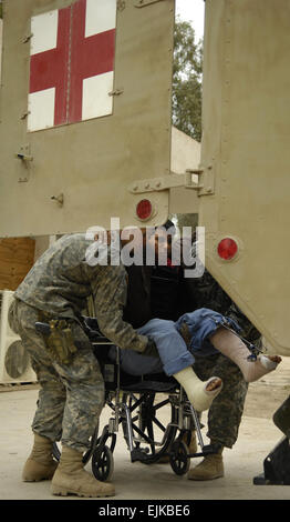 Infirmier de l'armée américaine le Sgt. Michael Daugherty, du 6e Bataillon, 9e régiment de cavalerie, 3e Brigade Combat Team, 1re Division de cavalerie, l'aide à soulever un agent de police irakiens blessés dans une ambulance à la base d'opérations avancée Normandie, l'Iraq, le 24 mars 2007. Le s.. Stacy L. Pearsall Banque D'Images