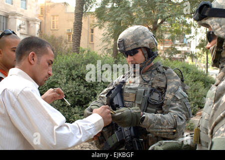 Le Major de l'armée américaine juge Anthony, droite, le directeur général du 1er bataillon du 504e Parachute Infantry Regiment, 1e Brigade Combat Team, 82e Division aéroportée, vérifie l'identification d'un homme avant d'autoriser son entrée dans le marché aux poissons d'Abu Nuwas dans la zone de sécurité de Rusafa, dans l'Est de Bagdad, l'Iraq, le 23 avril 2007. Des soldats de l'unité du juge assurent la sécurité pour revitaliser le secteur du marché. Le s.. Bronco Suzuki Banque D'Images