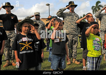 Les soldats du 3e Escadron, 4e régiment de cavalerie, 3e Brigade Combat Team, 25e Division d'infanterie, et junior Raiders, saluer durant l'hymne national pour commencer le trajet en épi Junior, le 21 mars, 2013 Le Schofield Barracks, à Hawaï. Banque D'Images