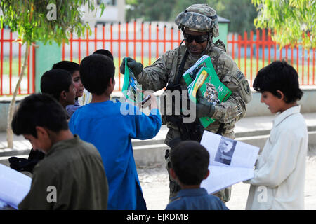 Le sergent de l'armée américaine. 1re classe Carl Coles, un membre des affaires civiles de l'Équipe de reconstruction provinciale Farah, distribue des magazines, tandis que les enfants locaux d'accueil et d'autres membres de la communauté lors d'une mission dans la province de Farah, de la ville de Farah, l'Afghanistan le 7 mai. PRT Farah est une unité de soldats, marins et aviateurs canadiens travaillant avec divers organismes gouvernementaux et non gouvernementaux chargés de faciliter la gouvernance et la stabilité dans la région en travaillant main dans la main avec les autorités locales et le Gouvernement de la République islamique d'Afghanistan. Le but de l'ERP est de promouvoir le gouvernement afghan et leur a Banque D'Images