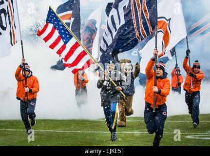 Le Sgt. Brian Abrams, Réserve de l'Armée de soldat du 863e bataillon du génie, la Compagnie de soutien de l'avant, porte le drapeau américain sur le terrain des membres de l'équipe de l'ours de Chicago sur le terrain avant les kickoff lors d'un match de la NFL désigné pour rendre hommage aux anciens combattants et membres du service militaire à Soldier Field, à Chicago, le 16 novembre. Le Sgt. 1re classe Michel Sauret Banque D'Images