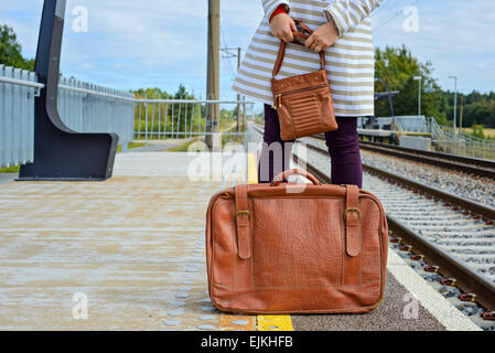 Womans mains tenant sac et valise à la station Banque D'Images