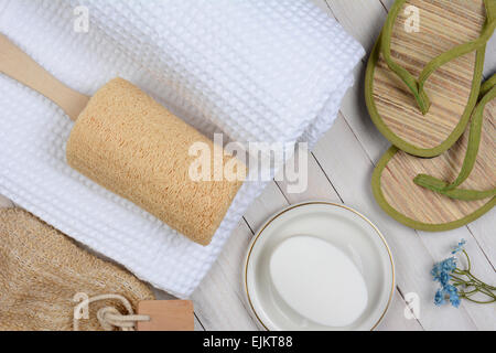 Baignoire Spa et la vie encore. High angle shot d'accessoires de salle de bains y compris, serviette, savon, loofah et sandales, on a rustic white w Banque D'Images