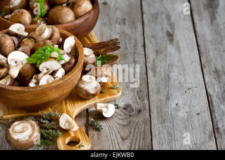 Matières premières fraîches portabello champignons avec couteau en bols en bois sur fond sombre Banque D'Images