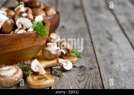 Matières premières fraîches portabello champignons avec couteau en bols en bois sur fond sombre Banque D'Images