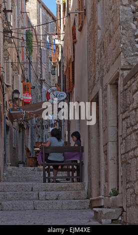 Les touristes orientaux dans un café dans la vieille ville de Korcula, rue étroite et de vieux bâtiments en pierre avec petite restauration. Banque D'Images