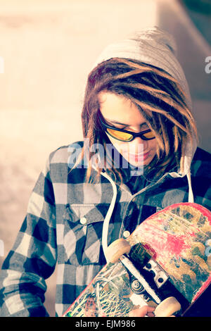 Portrait de jeune homme avec des cheveux rasta et skateboard focus sélectif dans un concept de vie filtre appliqué à chaud Banque D'Images