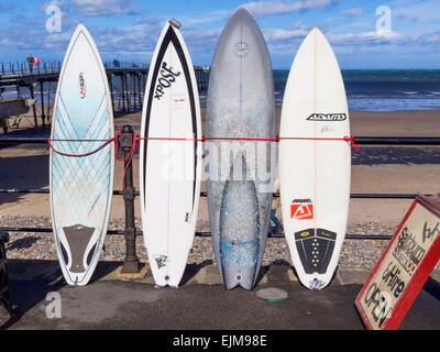 Planches de surf de mer liée contre la rambarde, à l'extérieur de la boutique par la jetée à Dharamsala, Cleveland, UK Banque D'Images