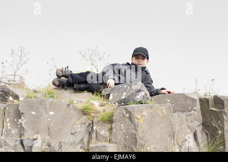 Portrait d'un enfant garçon détente sur la roche. Banque D'Images