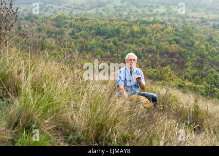 Happy senior man relaxing dans l'herbe et profiter de la nature verte. Banque D'Images