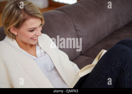 Woman Reading a book at home allongé sur le canapé Banque D'Images