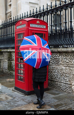 Femme avec parapluie Union Jack, cabine téléphonique, Londres Banque D'Images